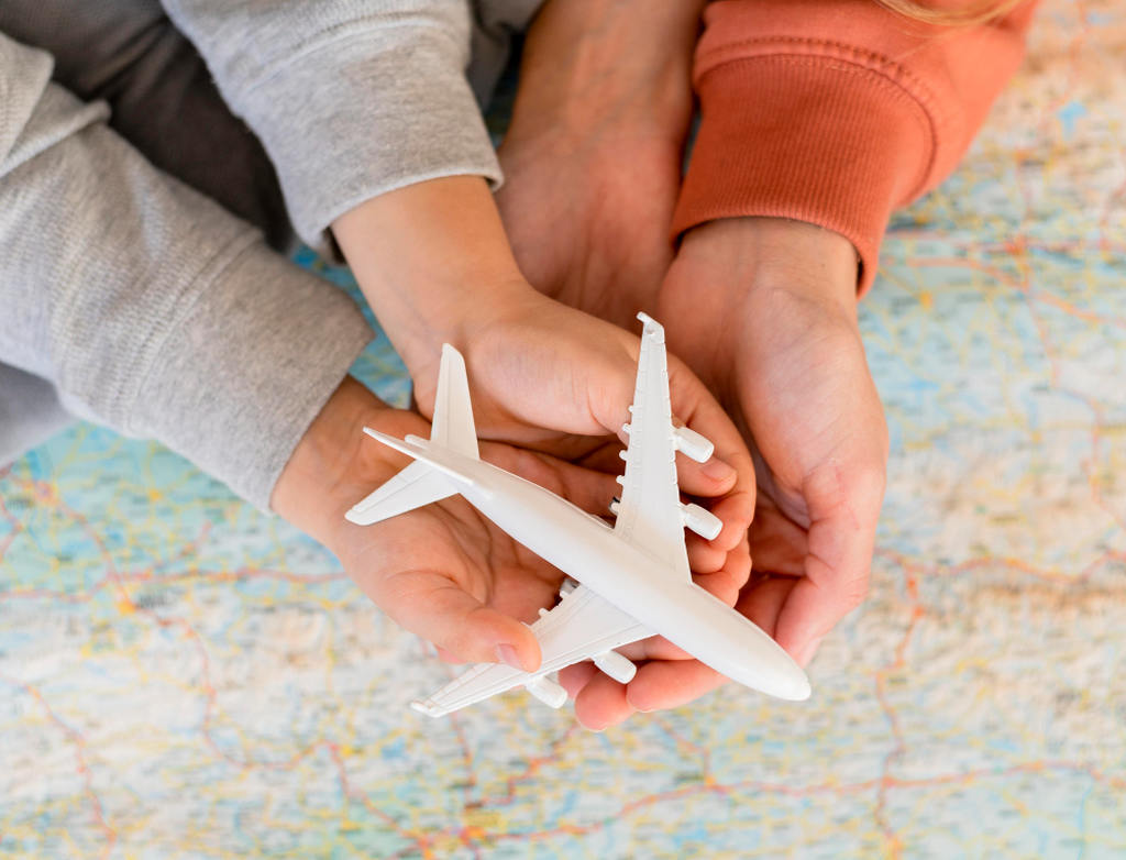 Mãos segurando um avião de brinquedo em cima de um mapa.
