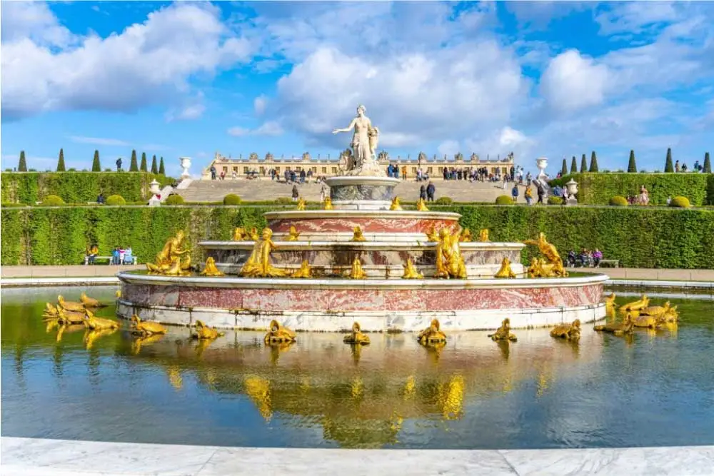 Fonte de Latona no Palácio de Versalhes, com esculturas douradas e o palácio ao fundo.