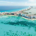 Vista aérea de península costeira da praia de Cancun com hotéis à beira-mar e águas turquesa.