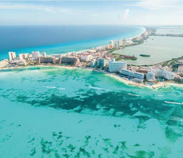 Vista aérea de península costeira da praia de Cancun com hotéis à beira-mar e águas turquesa.