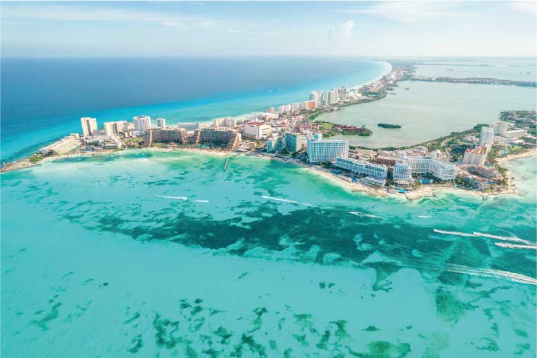 Vista aérea de península costeira da praia de Cancun com hotéis à beira-mar e águas turquesa.