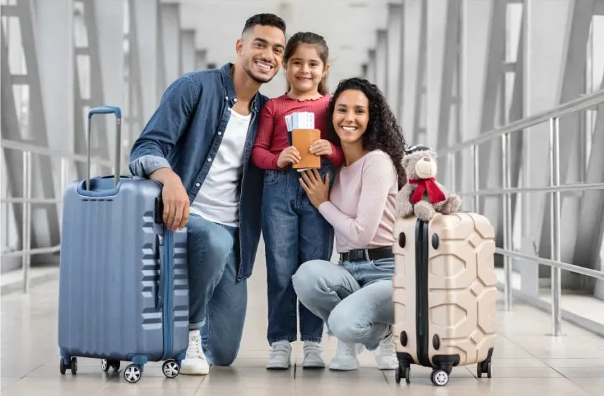 Família de três posando com bagagem em um terminal de aeroporto. A filha está segurando um passaporte e um bilhete.