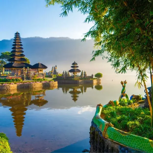 Templo Pura Ulun Danu Bratan em Bali, Indonésia, às margens do lago Bratan, com pagodes hindus refletidos na água, montanhas ao fundo, vegetação tropical e paisagem exótica ao amanhecer.