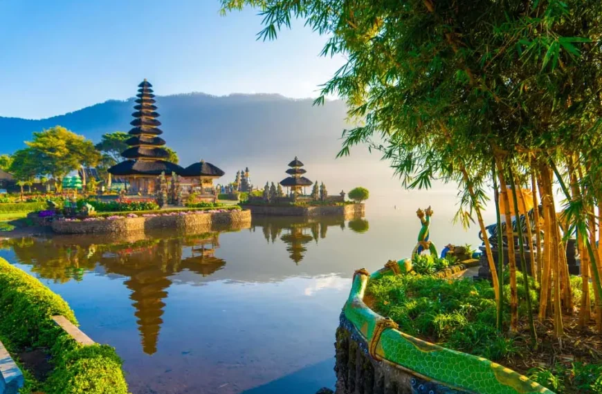 Templo Pura Ulun Danu Bratan em Bali, Indonésia, às margens do lago Bratan, com pagodes hindus refletidos na água, montanhas ao fundo, vegetação tropical e paisagem exótica ao amanhecer.