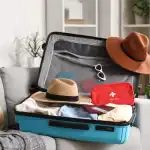 Maleta de viagem com roupas, chapéus e itens de proteção para viagem segura.