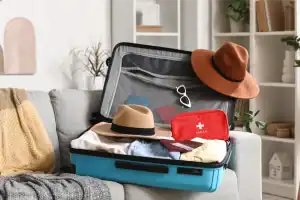 Maleta de viagem com roupas, chapéus e itens de proteção para viagem segura.