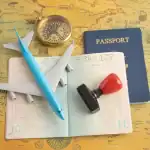 Itens de viagem, incluindo passaporte, avião de brinquedo, bússola e carimbo sobre mapa antigo.
