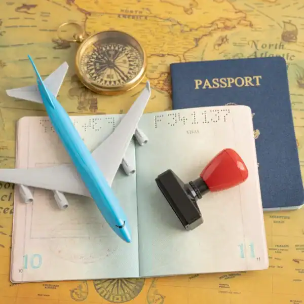 Itens de viagem, incluindo passaporte, avião de brinquedo, bússola e carimbo sobre mapa antigo.
