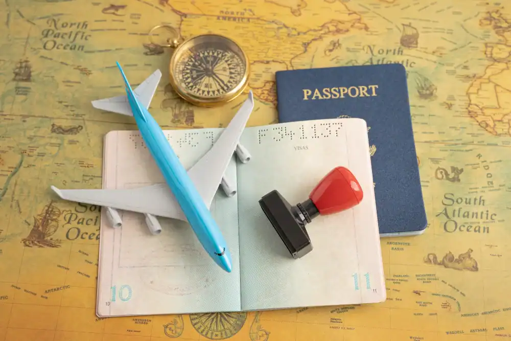 Itens de viagem, incluindo passaporte, avião de brinquedo, bússola e carimbo sobre mapa antigo.