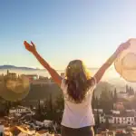 Mulher com chapéu aproveitando o pôr do sol na cidade, simbolizando liberdade e bem-estar.