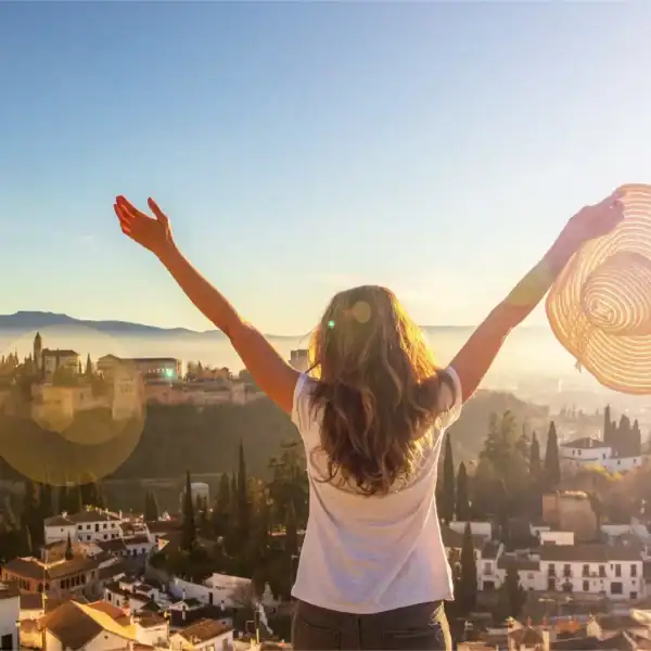Mulher com chapéu aproveitando o pôr do sol na cidade, simbolizando liberdade e bem-estar.