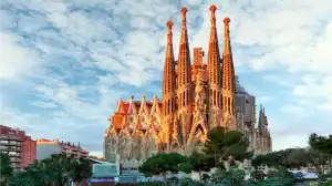 Catedral de Barcelona vista do parque com céu azul e nuvens, destaque na arquitetura gótica.