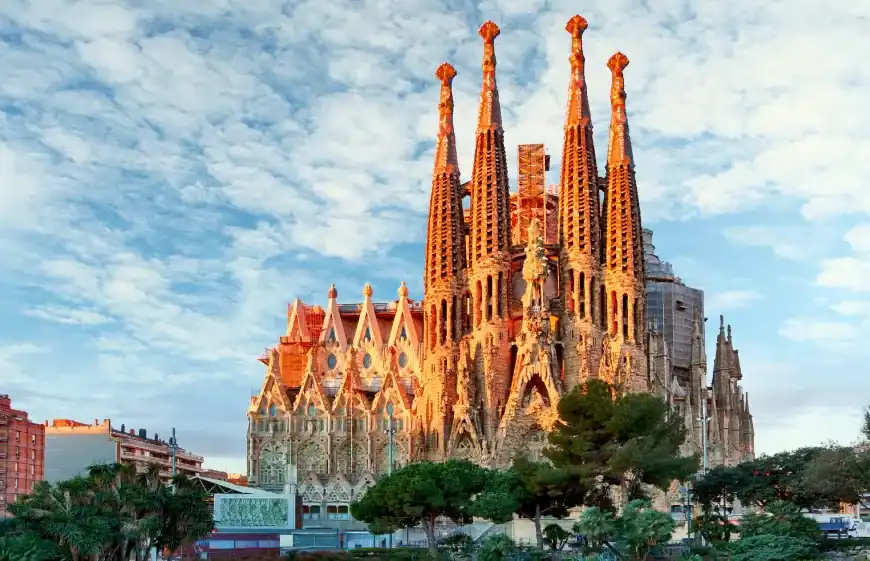 Catedral de Barcelona vista do parque com céu azul e nuvens, destaque na arquitetura gótica.