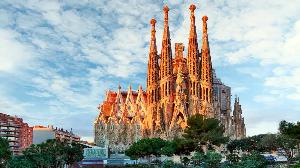 Catedral de Barcelona vista do parque com céu azul e nuvens, destaque na arquitetura gótica.