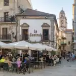 Café ao ar livre na Espanha com pessoas desfrutando de refeições.