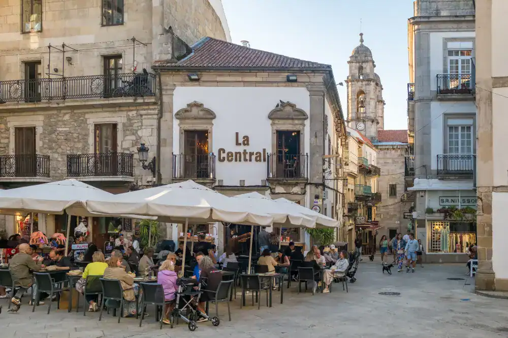 Café ao ar livre na Espanha com pessoas desfrutando de refeições.
